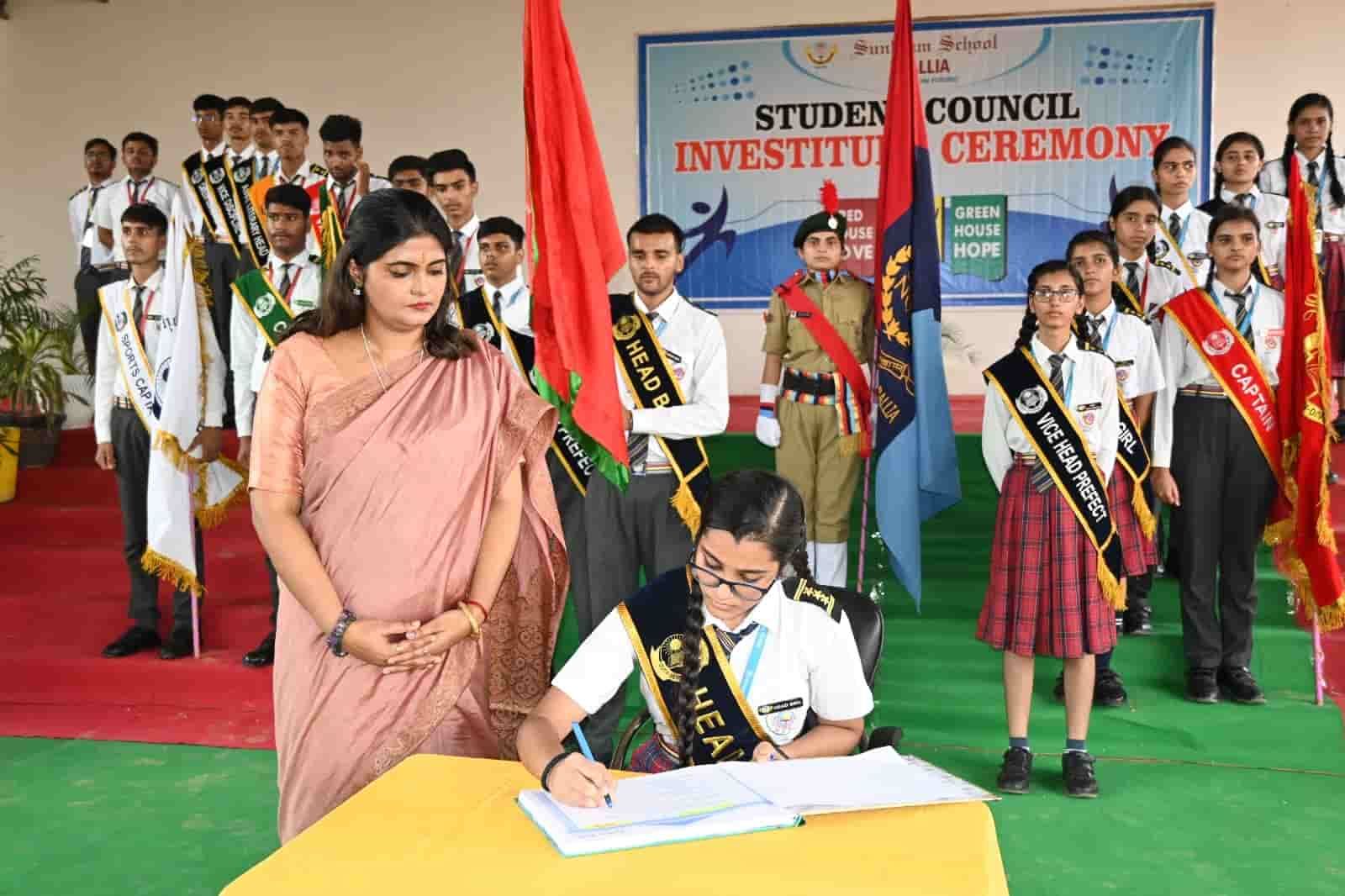 The student council investiture ceremony at Sunbeam School Ballia, office-holders standing in sashes with the house flags behind them.